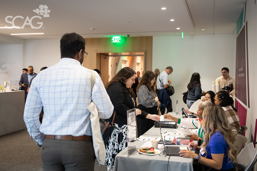 People interacting at a conference registration desk.
