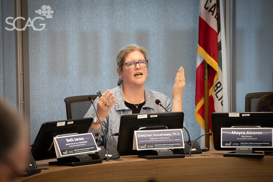 Woman speaking at a conference table with multiple microphones.