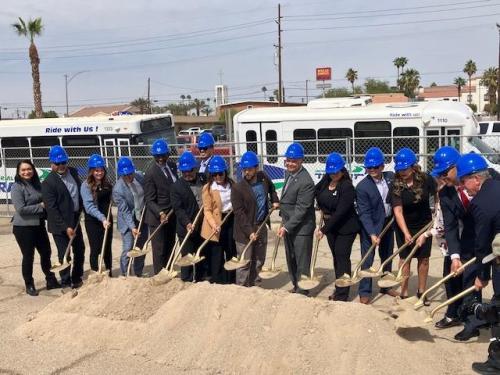 People wearing blue ball caps with shovels in their hand.
